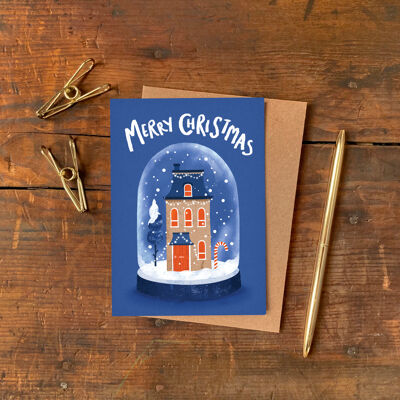 Tarjeta de Navidad con bola de nieve y casa festiva