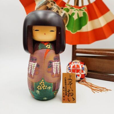 Yosooi bemalte die hölzerne Kokeshi-Puppe mit einem lila Blumenmuster