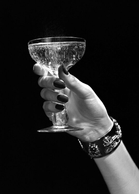 Mano che tiene la cartolina d'auguri in bianco di vetro di champagne