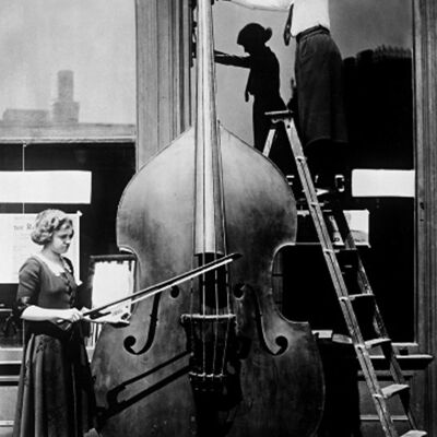Due donne con una cartolina d'auguri in bianco molto grande del violoncello