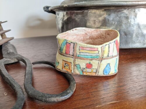 Clay bangle bracelet featuring a hand painted bookcase scene