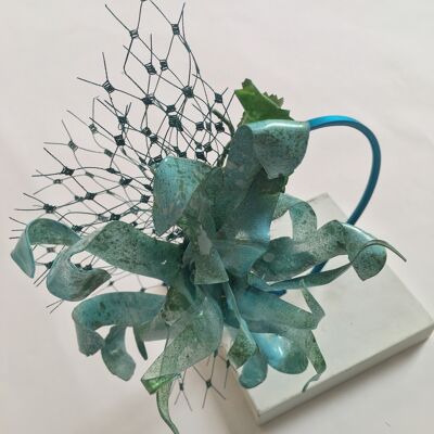 Turquoise and green recycled plastic flower on a turquoise silk metal covered headband.