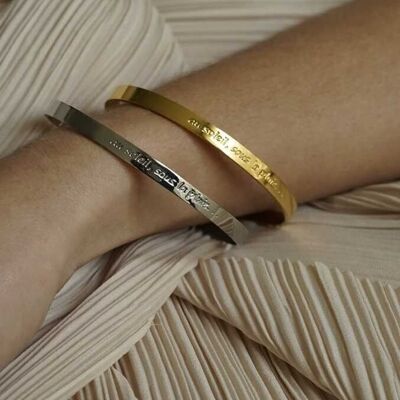 Bracciale rigido in acciaio argentato inciso al sole, sotto la pioggia