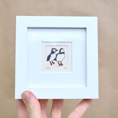 Two puffins standing close and looking at each other - mini collagraph print in a white frame