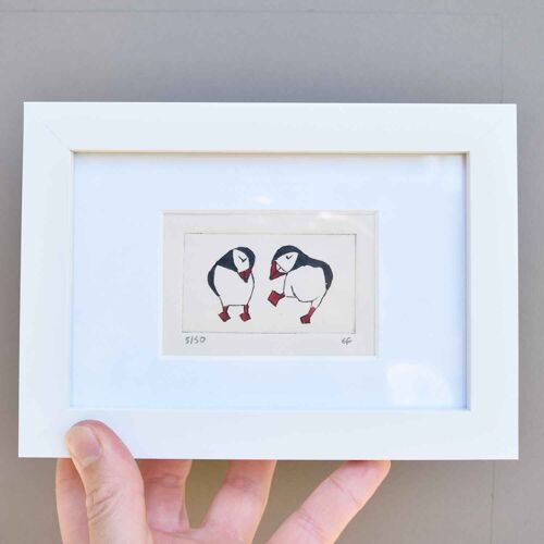 Two puffins, one dancing one coy - collagraph print in a white frame