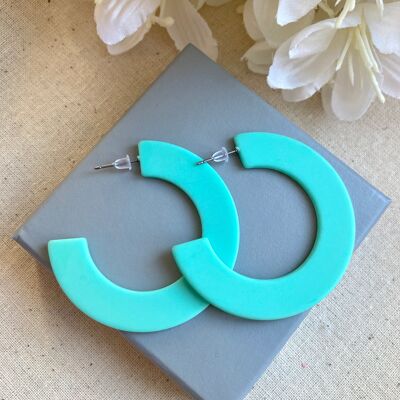 Thick turquoise resin hoop earrings.