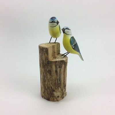 Two great tits on a tree trunk made of wood in the colors blue and yellow