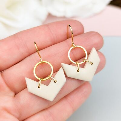 Pendientes colgantes neutros, con charm circular bañado en oro.