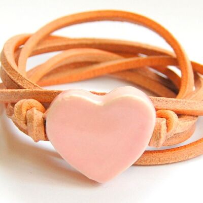 Cordón de cuero natural con corazón de cerámica rosa claro.