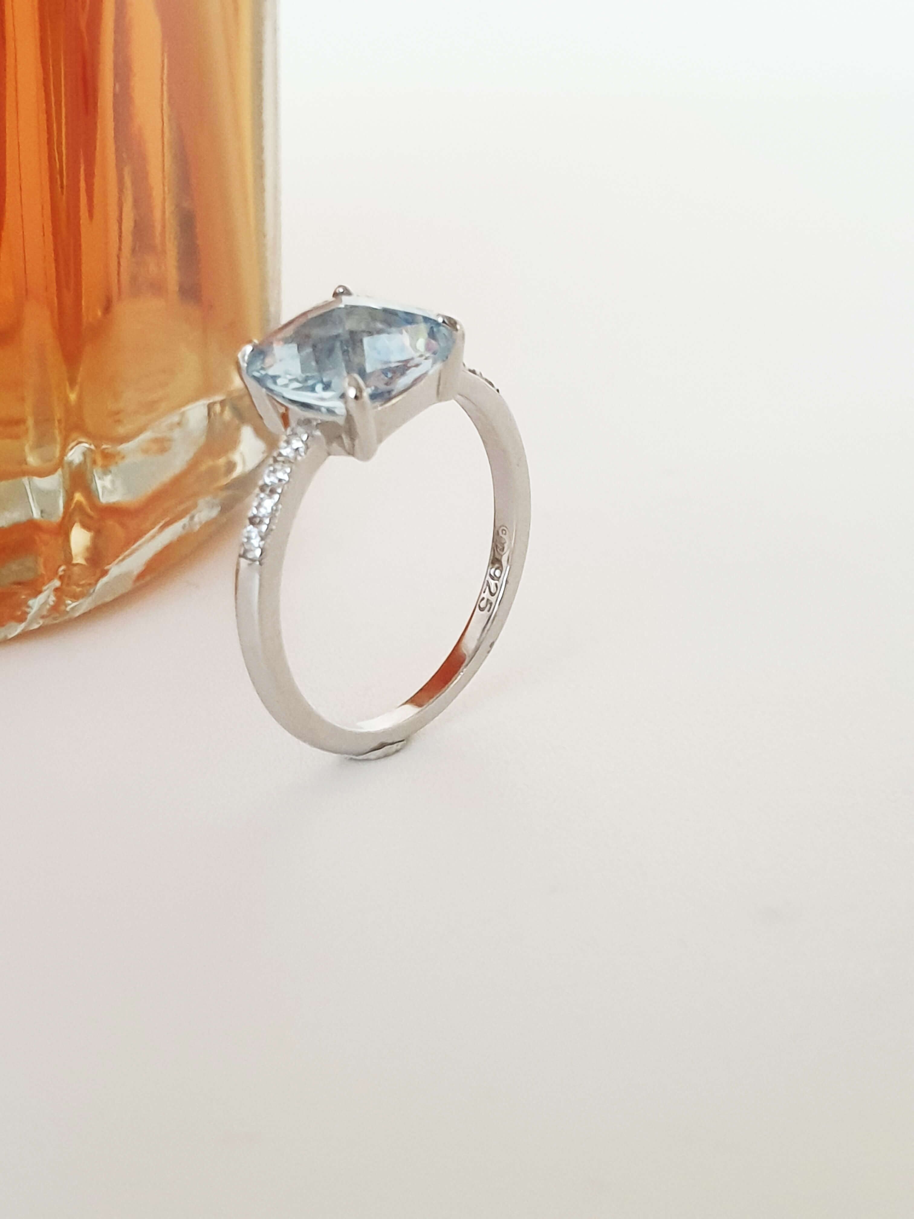 Anello in argento 925/1000 rodiato, con ossidi di zirconio, sormontato da un quadrato in pietra sintetica sfaccettata azzurra