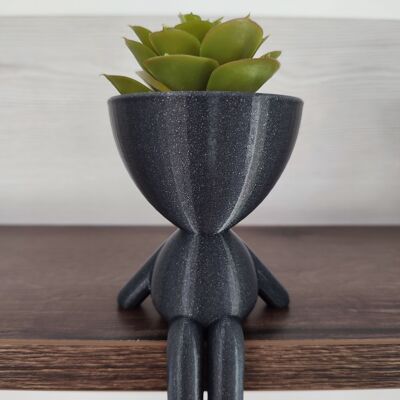 Flowerpot in the shape of a person sitting on the edge