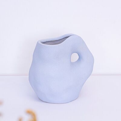 Jarrón de cerámica esculpida en azul hielo, estilo minimalista y orgánico.