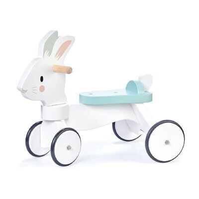 Paseo en conejo corriendo sobre un juguete con ruedas de madera de hoja tierna