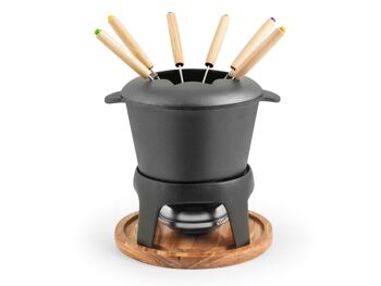 Service à fondue 11 pièces en fonte avec socle en bois. Composé de : 6 fourchettes en acier inoxydable avec manche en bois ; 1 réchaud à pâte combustible ; 1 casserole en fonte 21x16x10 h cm avec pare-éclaboussures; 1 socle cm 17x9 h; 1 socle en bois cm 19,5x2 h 5