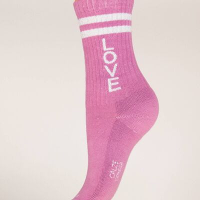 Calcetines deportivos de mujer con amor escrito sobre un fondo rosa