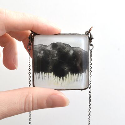 Glasanhänger mit einer schwarzen Gewitterwolke.