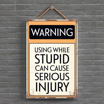 P1606 – Warnung, dass die Verwendung während Dummheit Verletzungen verursachen kann. Typografisches Schild, gedruckt auf einer hölzernen Hängeplakette
