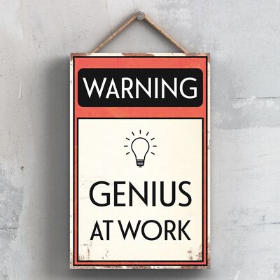 P2089 - Señal tipográfica de advertencia Genius At Work impresa en una placa colgante de madera