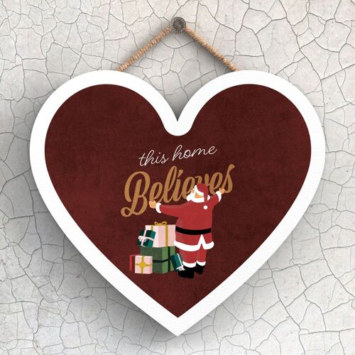 P2429 - This Home Believes Santa With Presents Typography On A Heart Shaped Wooden Hanging Plaque
