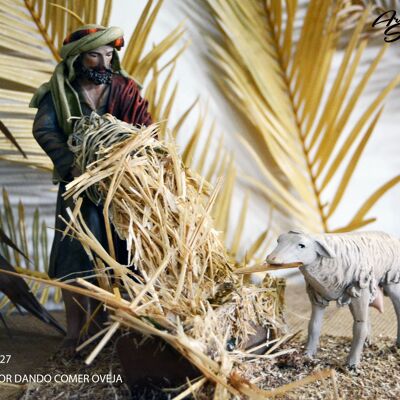 Pastor dando de comer a oveja, figura del belén