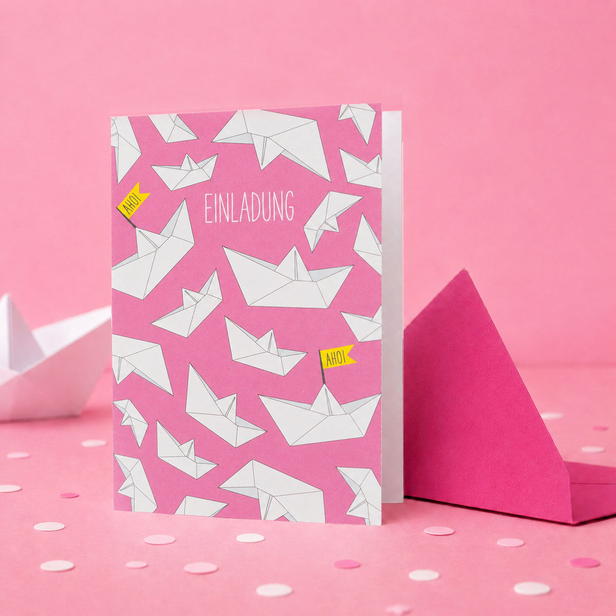 Tarjeta de invitación para una fiesta de cumpleaños infantil con barquitos de papel en color rosa.