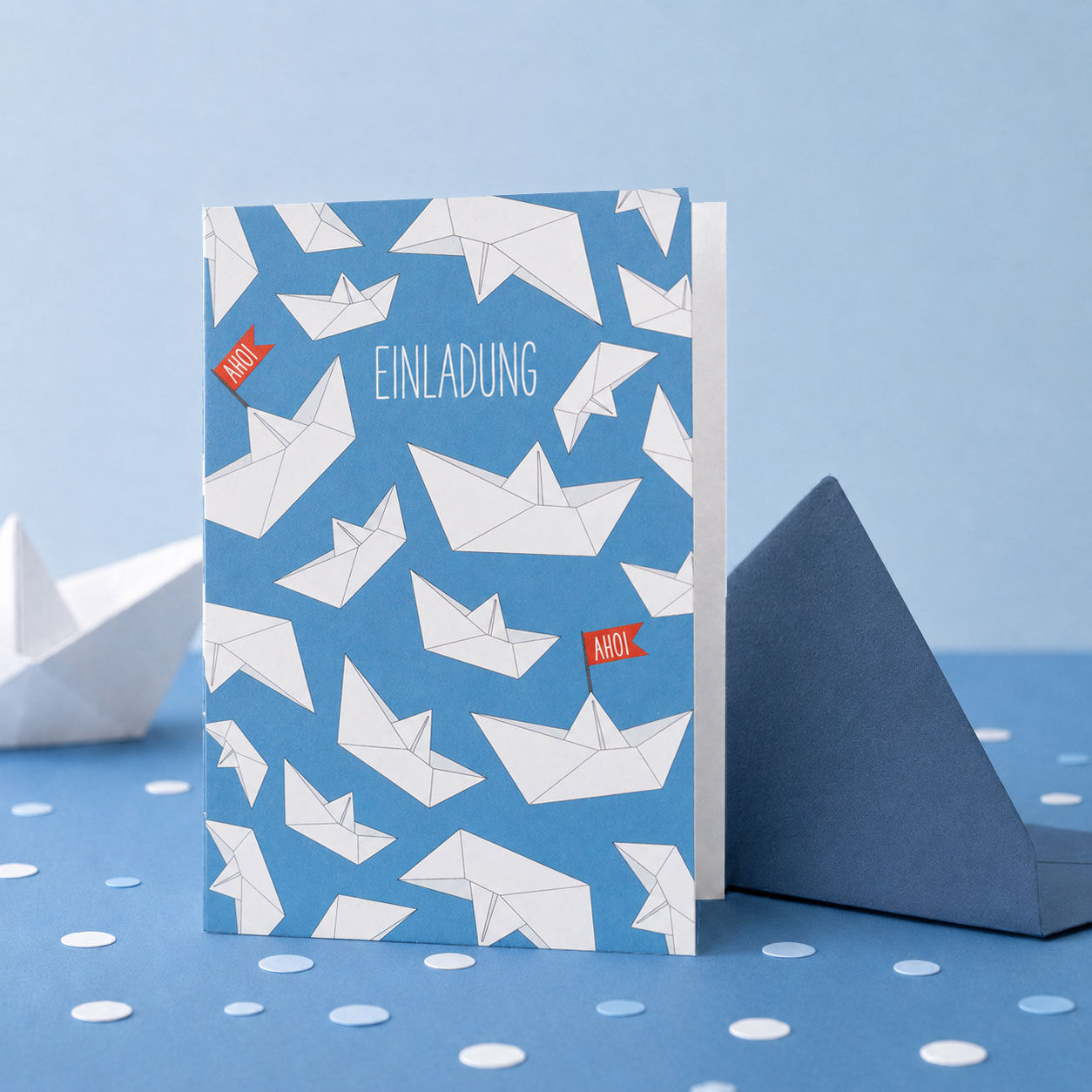 Tarjeta de invitación para una fiesta de cumpleaños infantil con barquitos de papel en color azul.