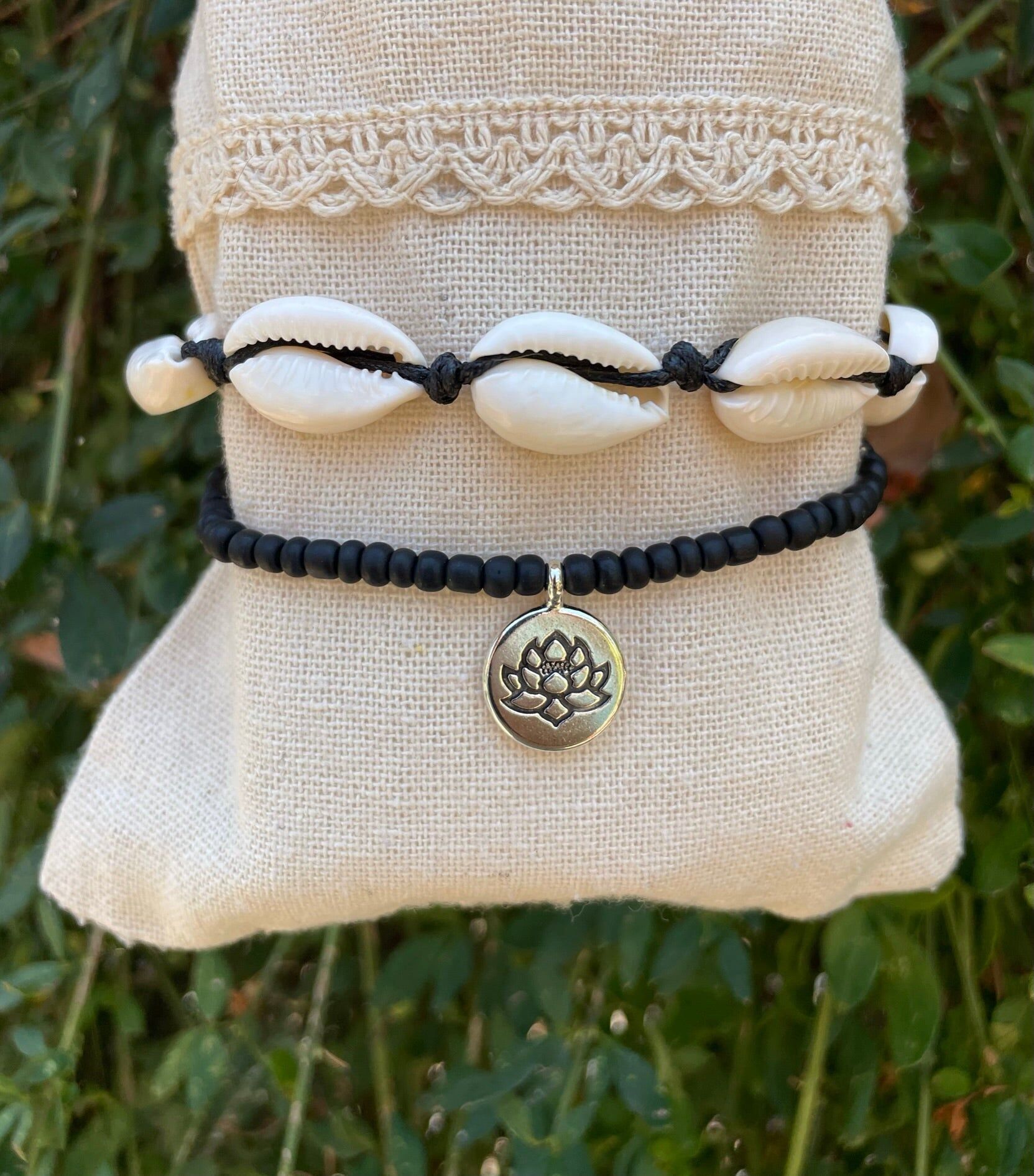 Cadena de tobillo negra en conchas de cauri y loto.