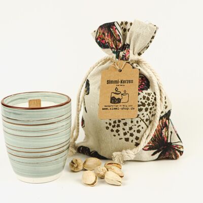 Vela perfumada crepitante hecha a mano con cera de colza natural con aroma a pistacho en una taza de cerámica