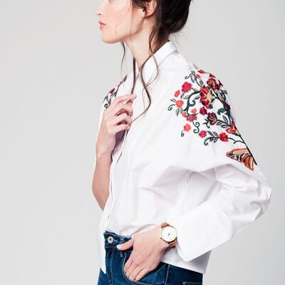 Blusa blanca con detalle de bordado de flores en las mangas.