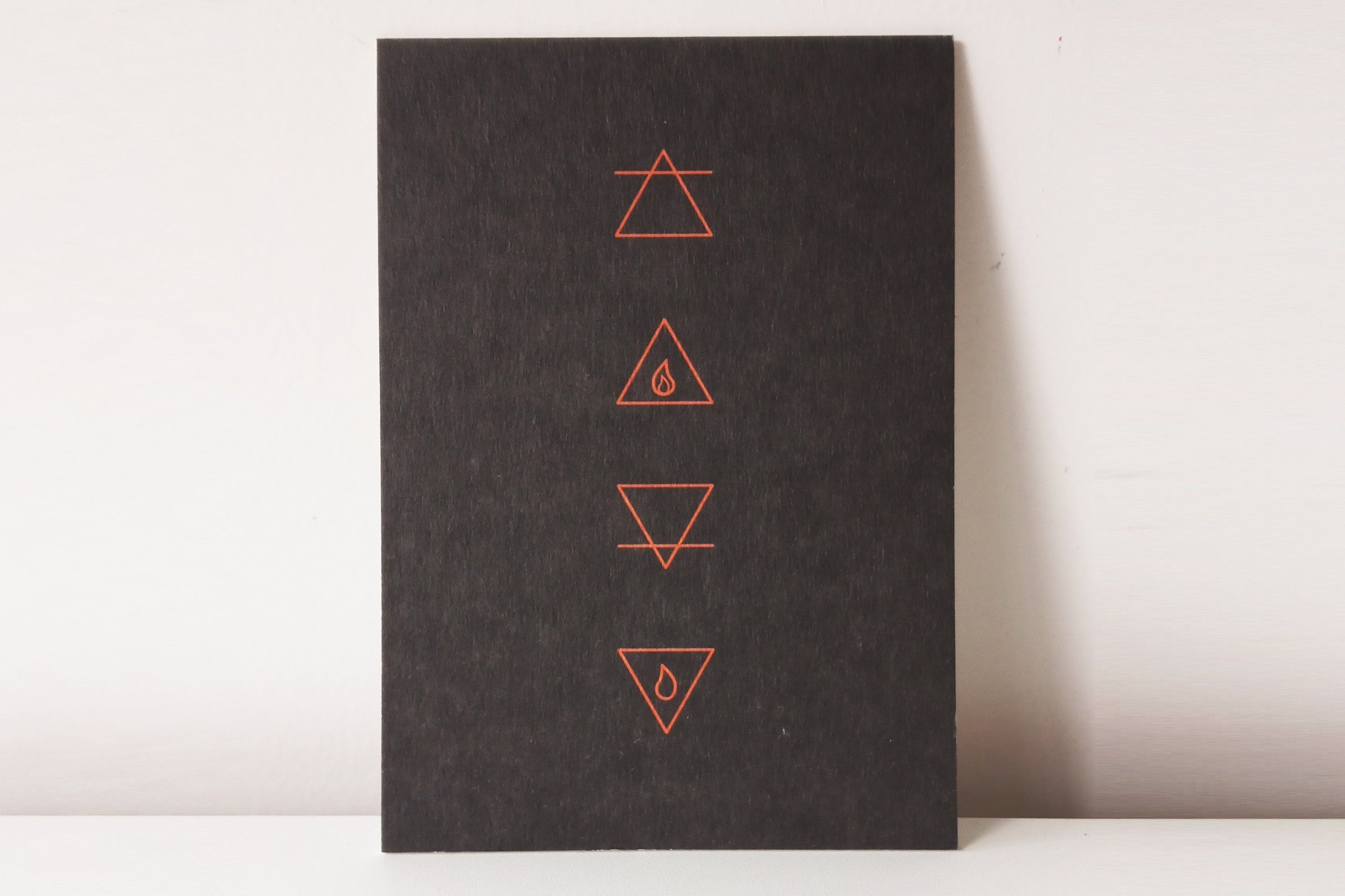 Postkarte "Vier Elemente" - die Symbole der vier Elemente in koralle und dunkelbraun auf fester Holzschliffpappe gedruckt