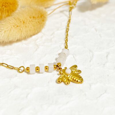 Pulsera de cadena dorada con abeja blanca.