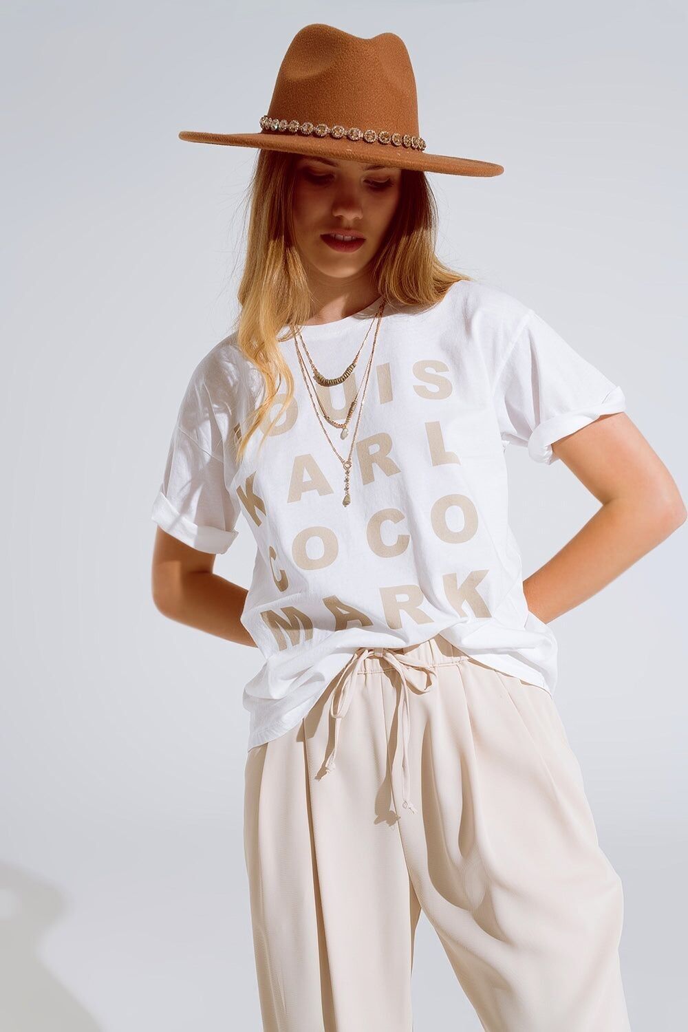 T-shirt color crema con loghi di nomi famosi sul davanti