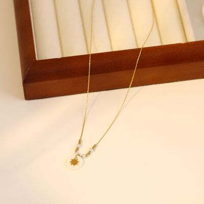 Gold pearl and pearl necklace with sun pendant on mother-of-pearl