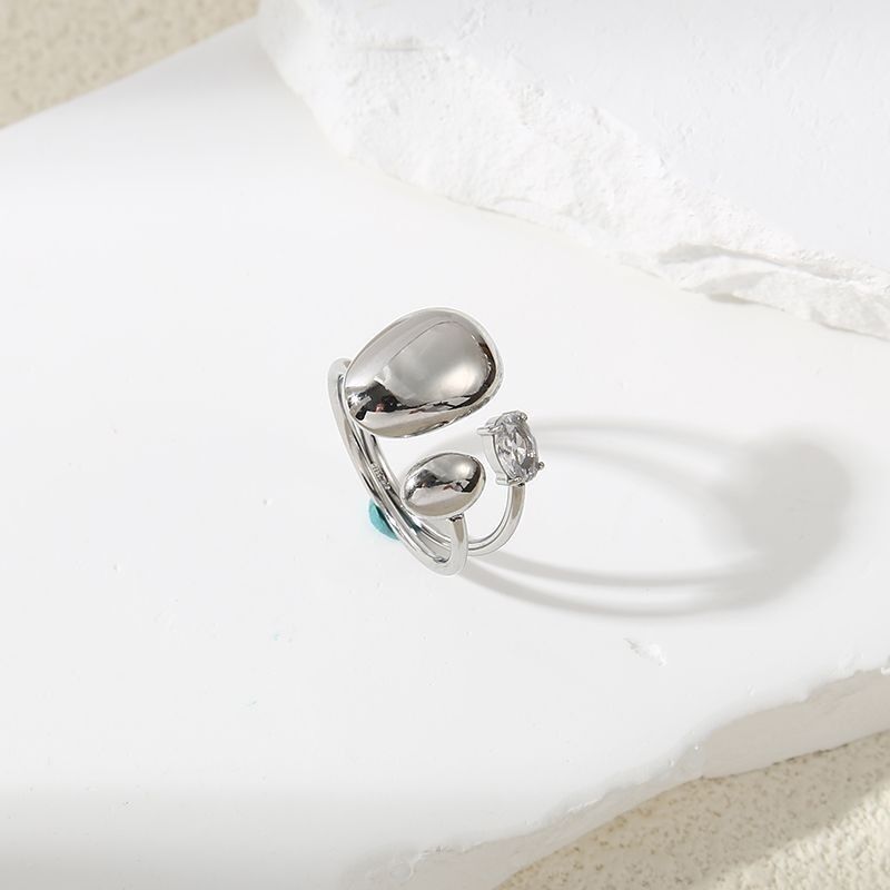 Silberring mit unregelmäßigen ovalen Plättchen und spitzen Strasssteinen