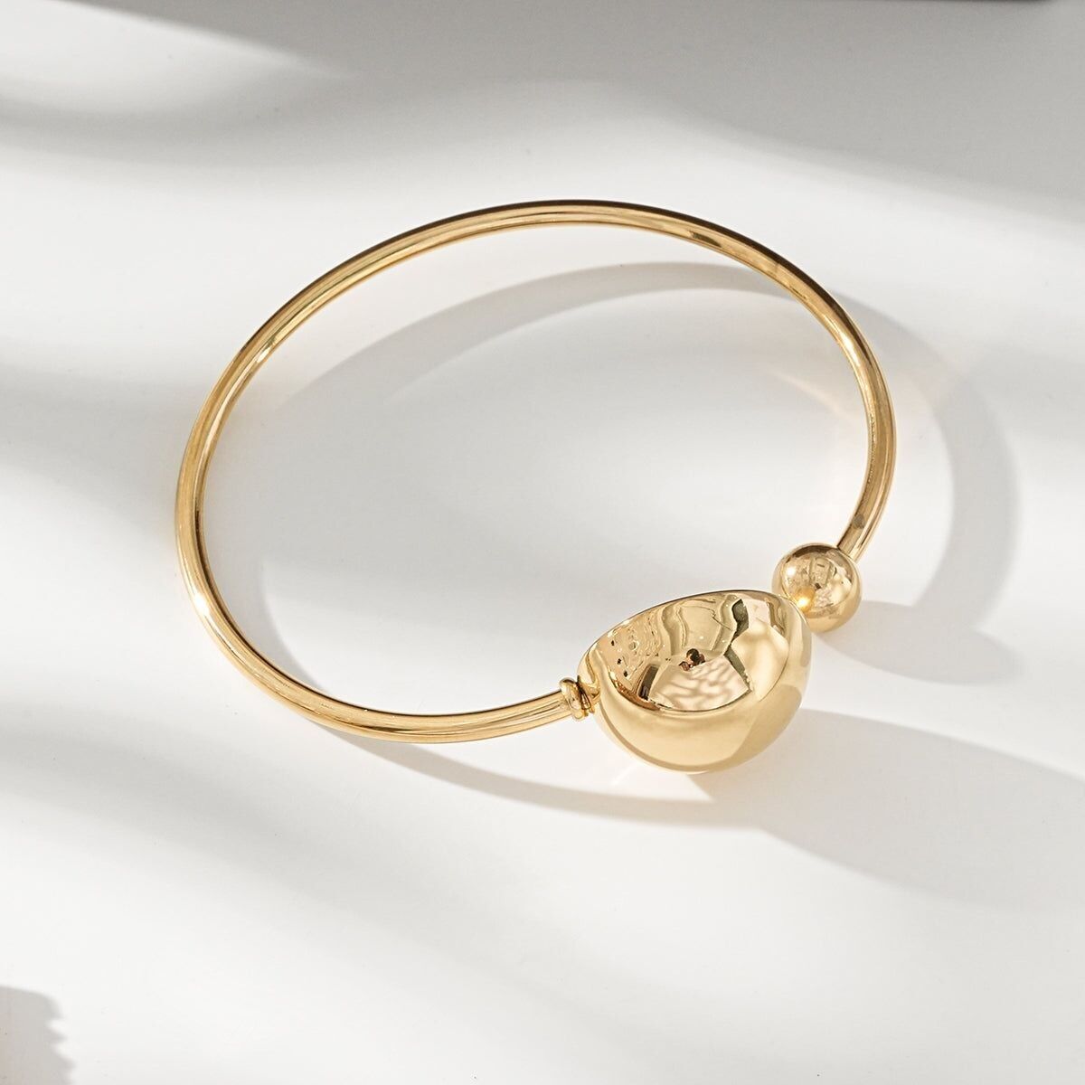 Bracciale rigido dorato con semisfera e pallina di brillanti removibili