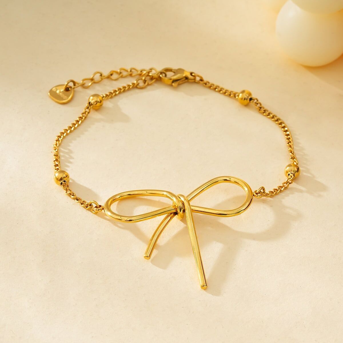 Bracciale a catena dorata decorato con palline dorate con grande papillon