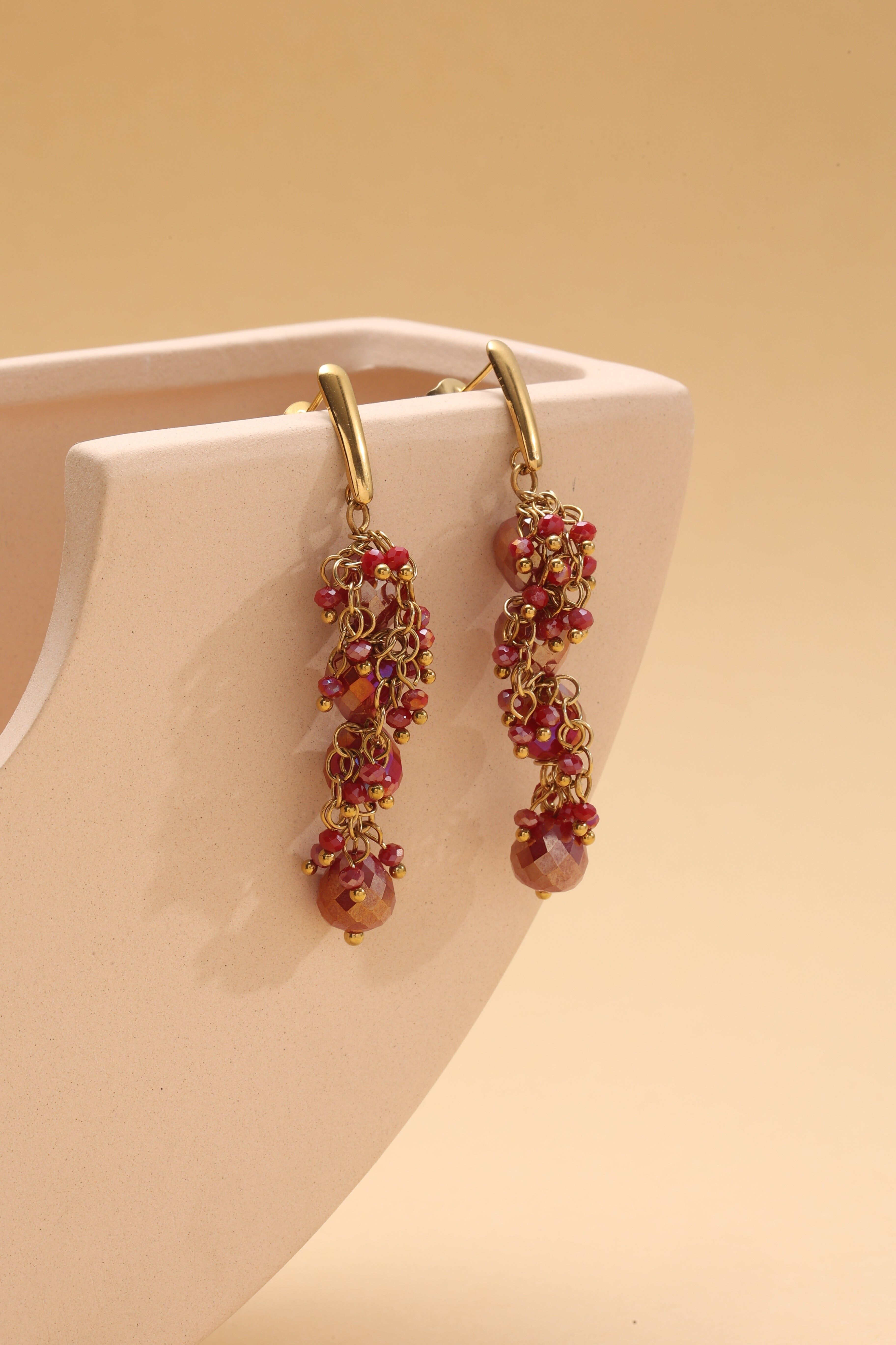 Orecchini pendenti in oro con catena in cristallo rosso e finiture raffinate
