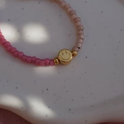 Pulsera hecha a mano con colgante de cuentas de vidrio con cara sonriente bañada en oro.