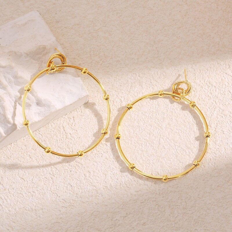 Orecchini pendenti con cerchio dorato e sfera strutturata