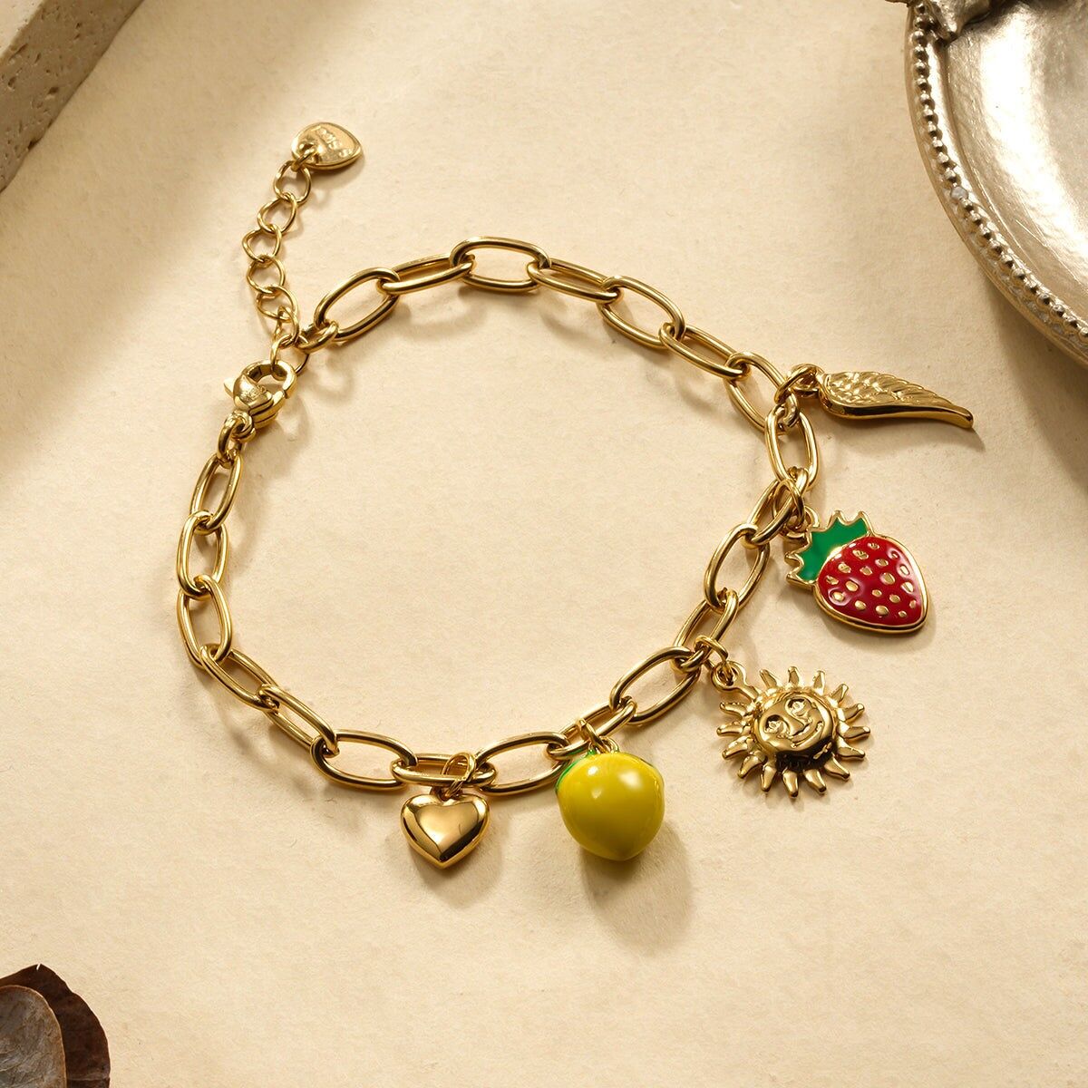 Bracciale in oro con ciondoli a forma di limone, fragola e sole