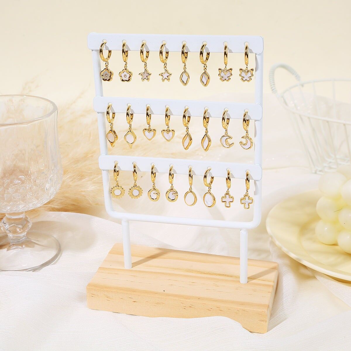 Set mit 12 Paar Mini-Creolen aus Perlmutt auf weißem Präsentationsständer