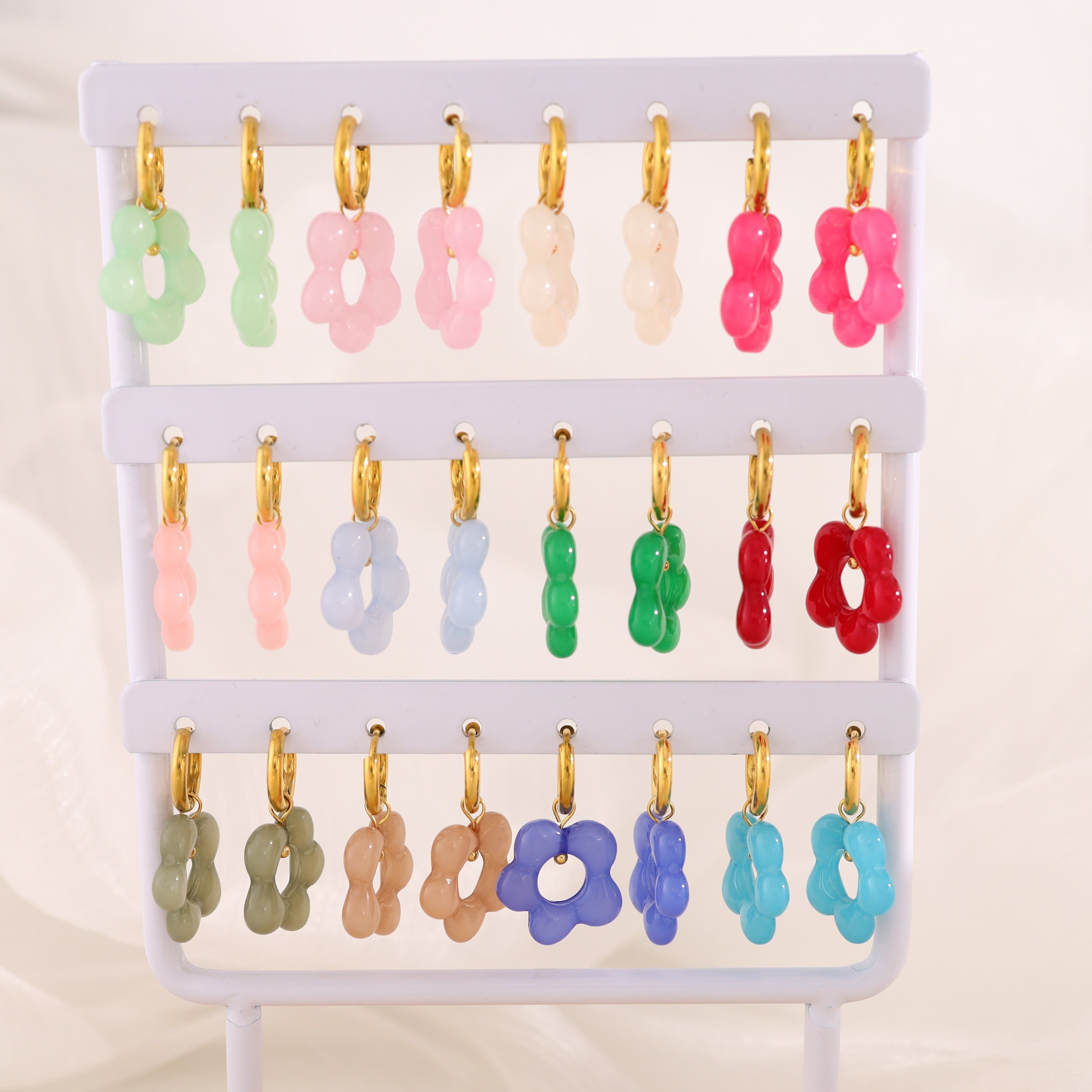 Set di orecchini a cerchio con fiori in resina colorata su espositore bianco