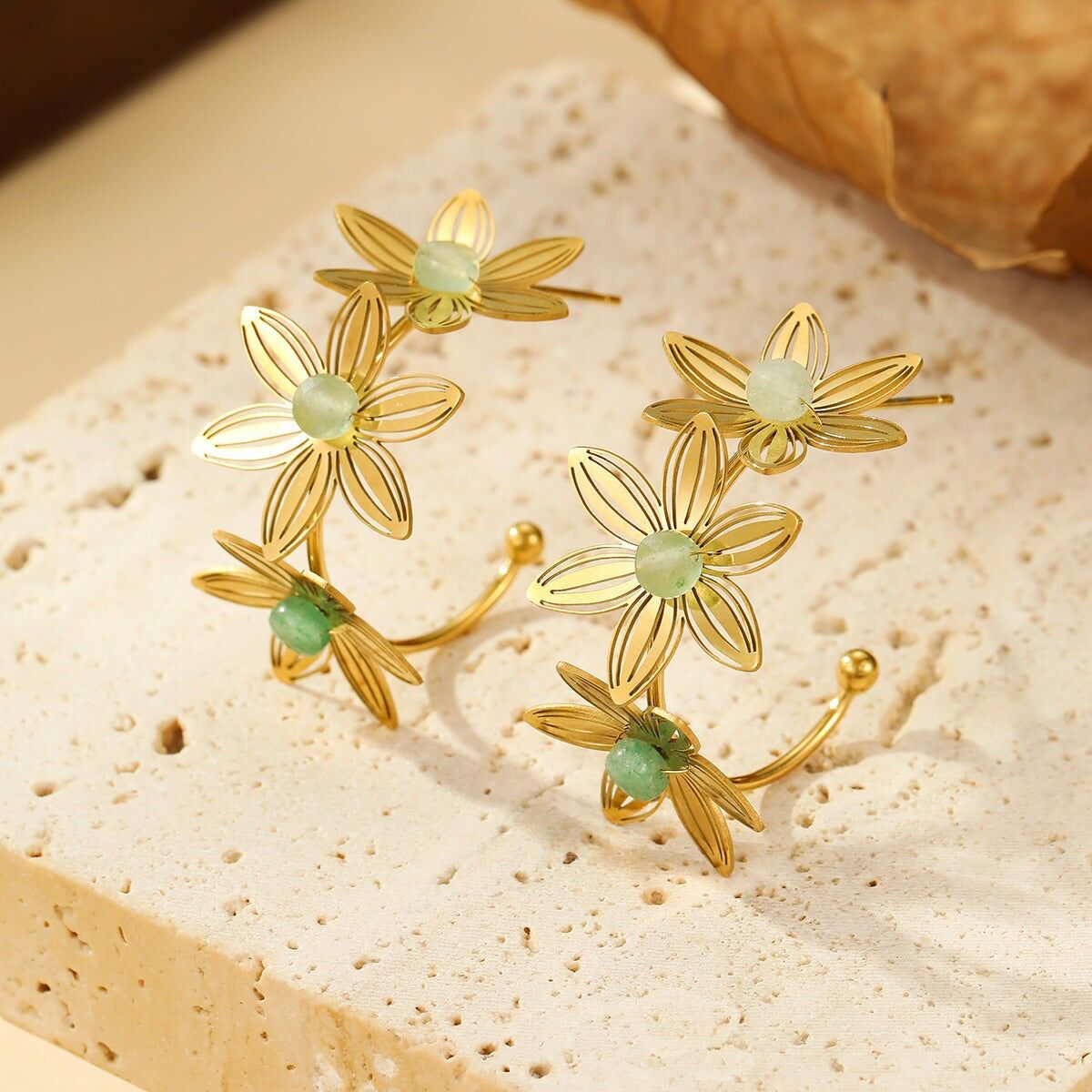 Orecchini a cerchio in oro con triplo fiore traforato e pietre verdi