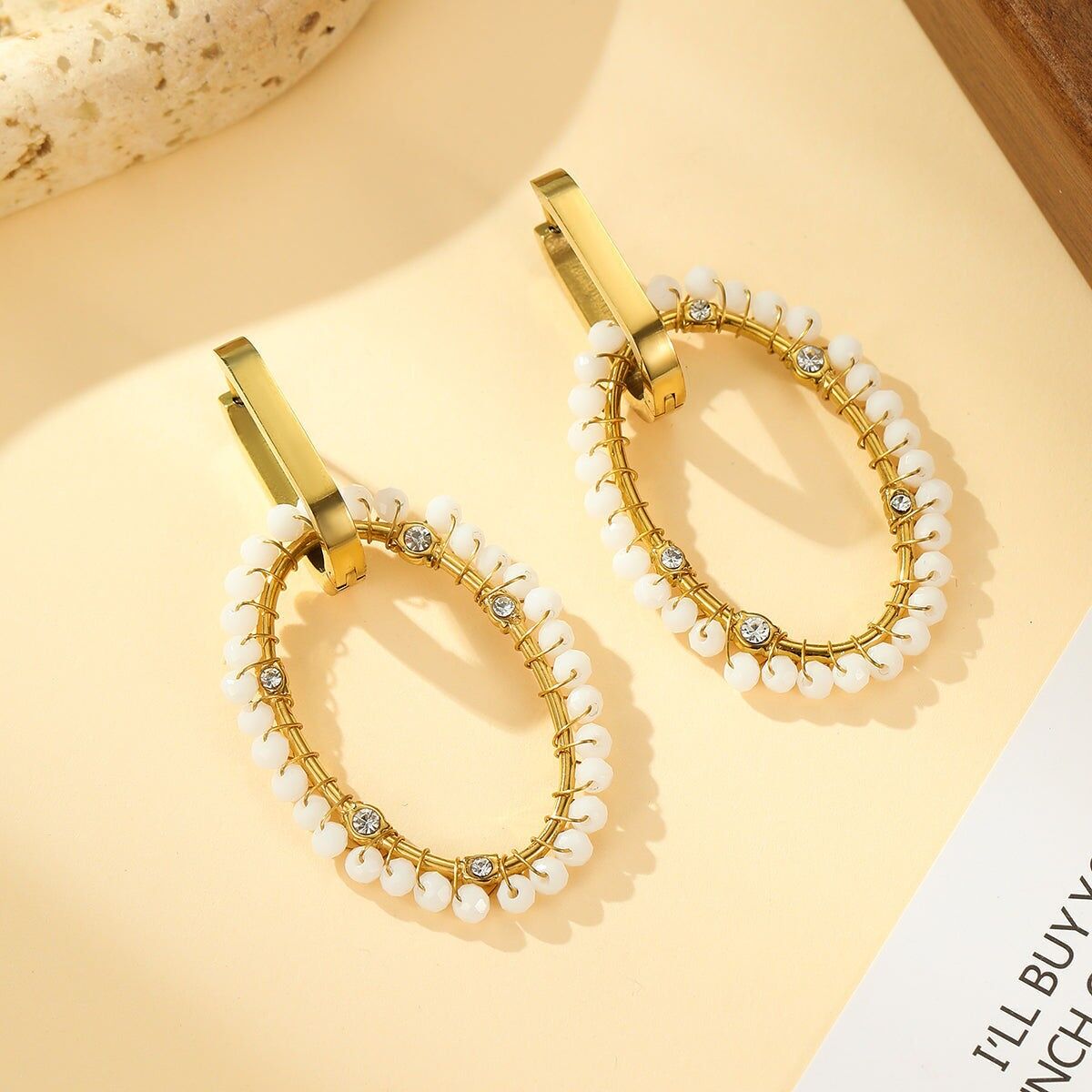 Orecchini a cerchio ovali in oro intrecciati con pietre bianche e strass