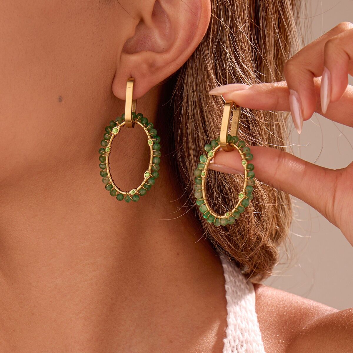 Orecchini a cerchio ovali in oro intrecciati con pietre verdi e strass