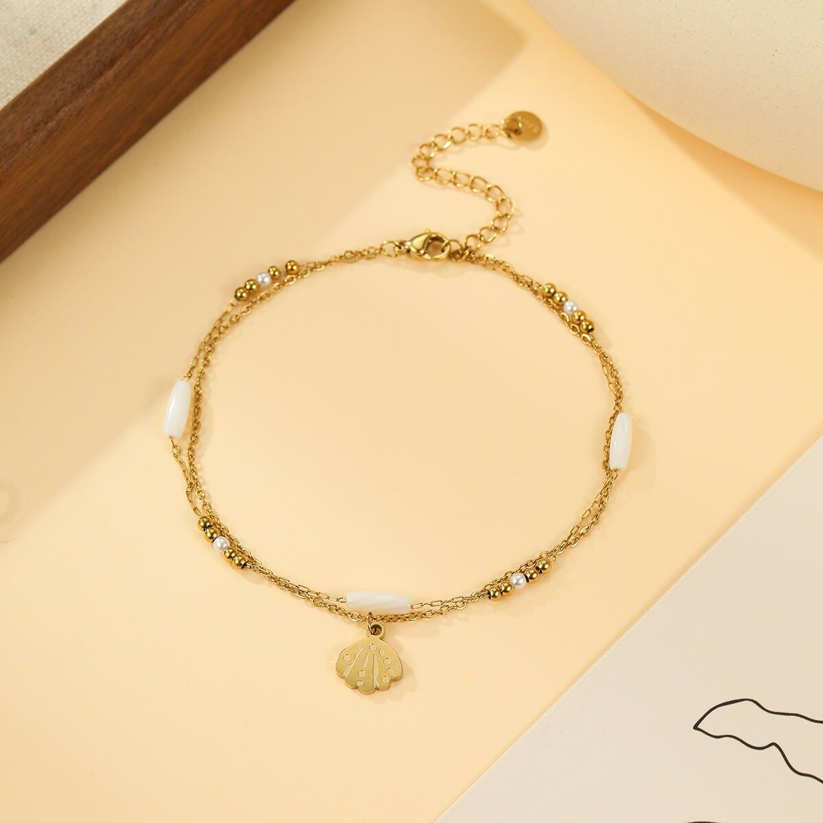 Cavigliera a doppia catena in oro e ciondolo a conchiglia