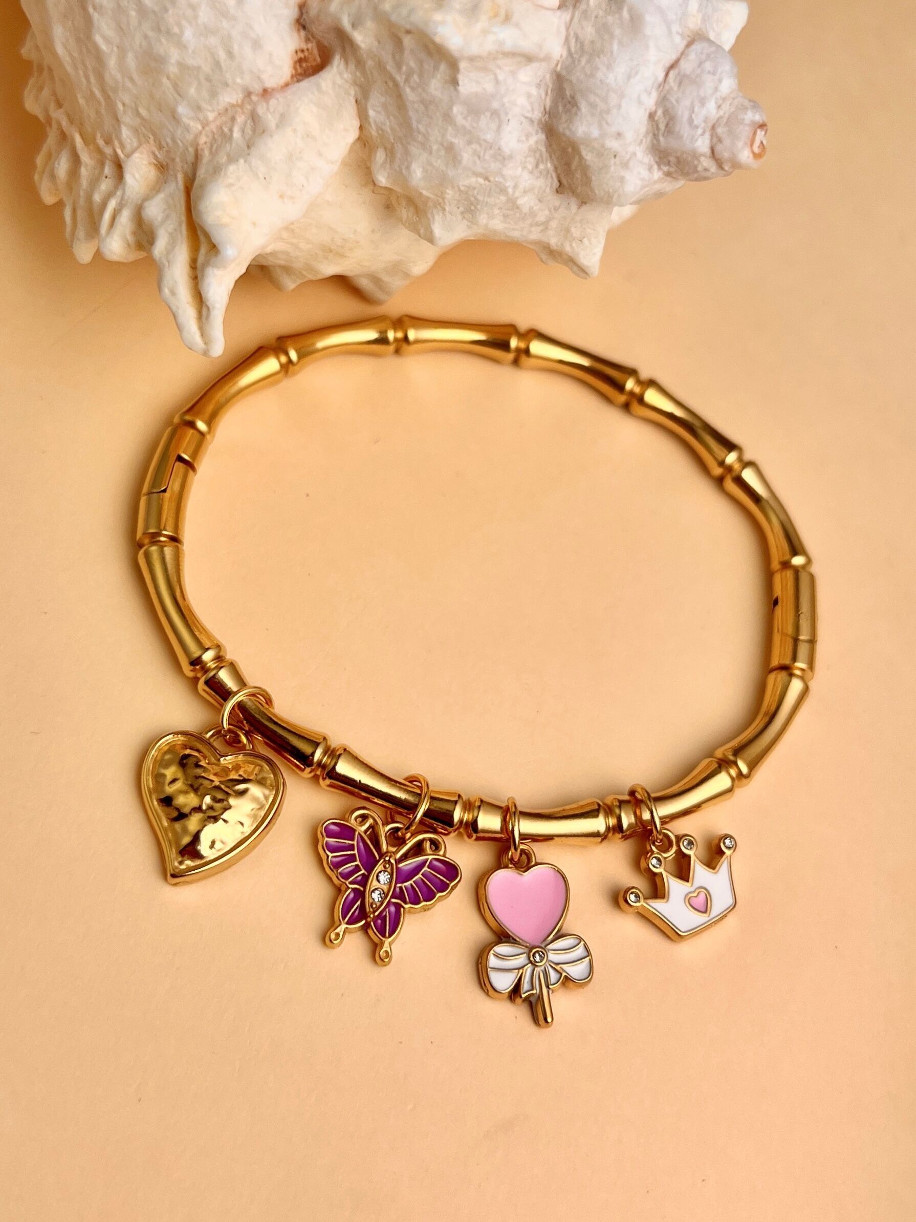 Pulsera brazalete con charms de mariposa, corazón y corona en acero