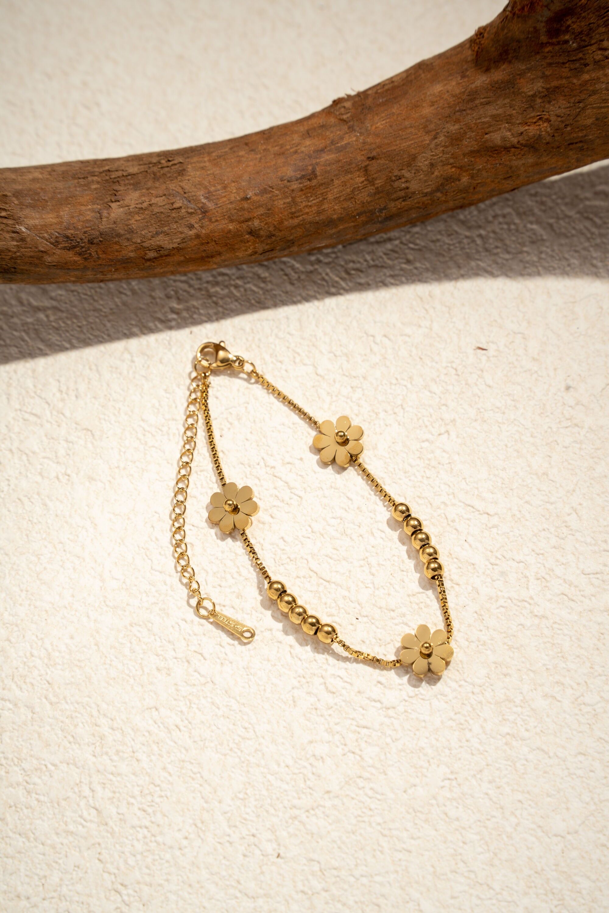 Pulsera refinada con motivo de margaritas y cuentas de acero dorado.