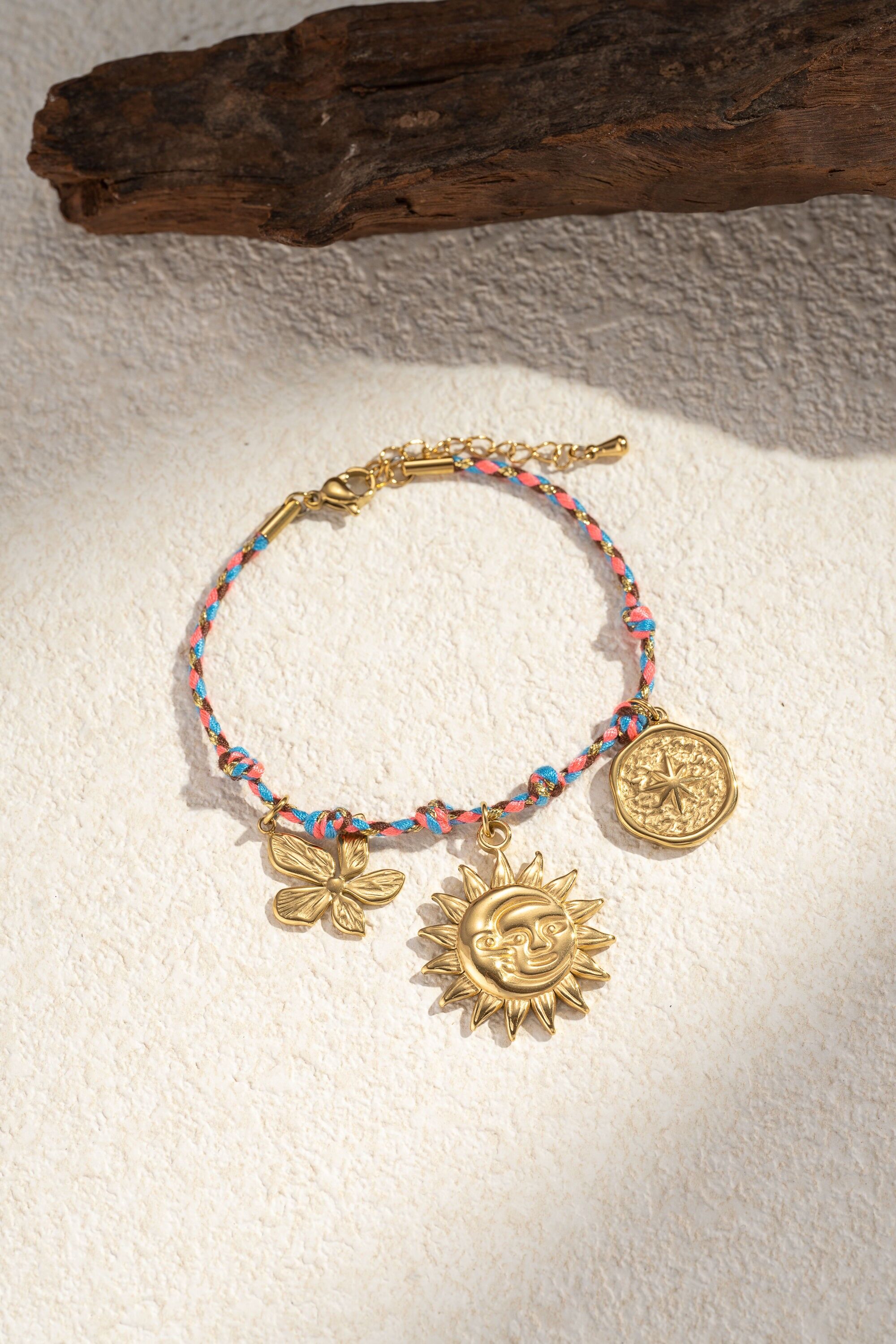 Pulsera de cuerda trenzada con dijes de flores, sol y luna.