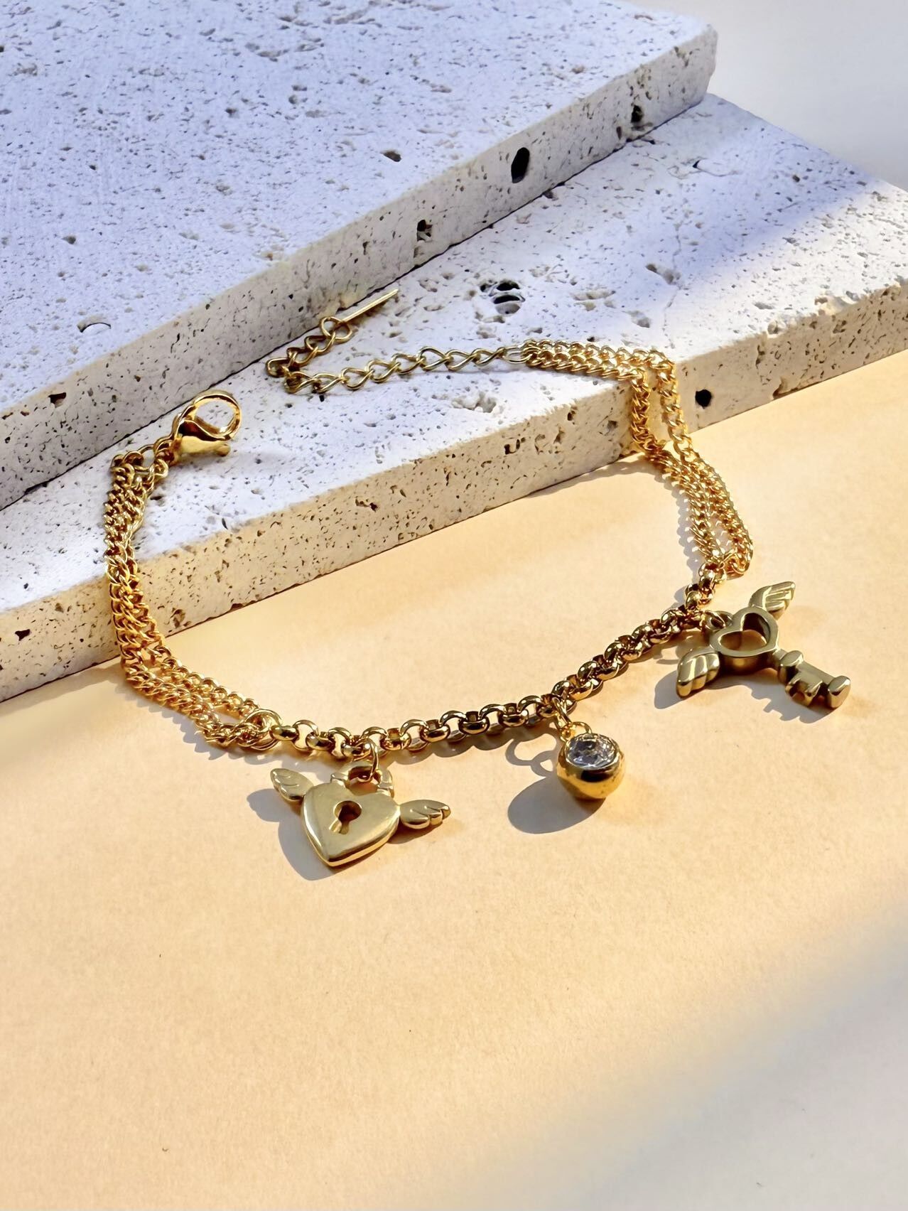 Pulsera de acero inoxidable con charms de corazón, llave y cristal.